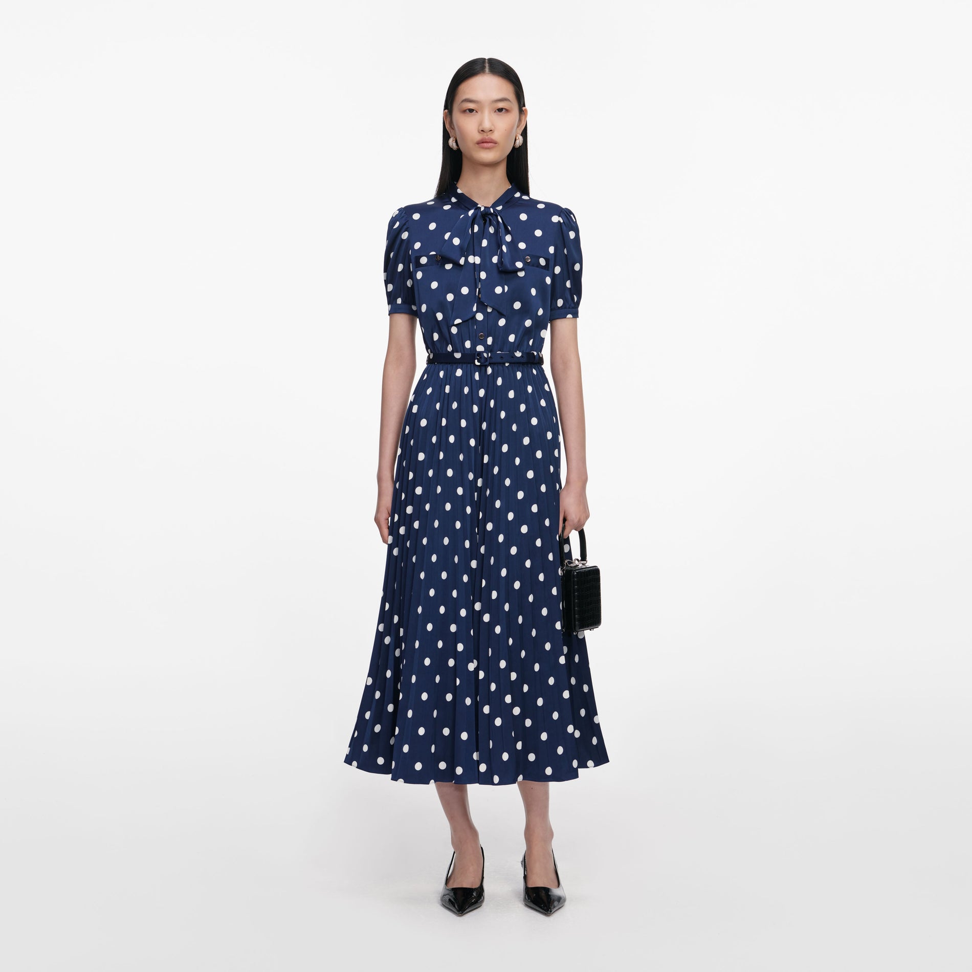 Front view of a woman wearing the Navy Polka Dot Satin Midi Dress