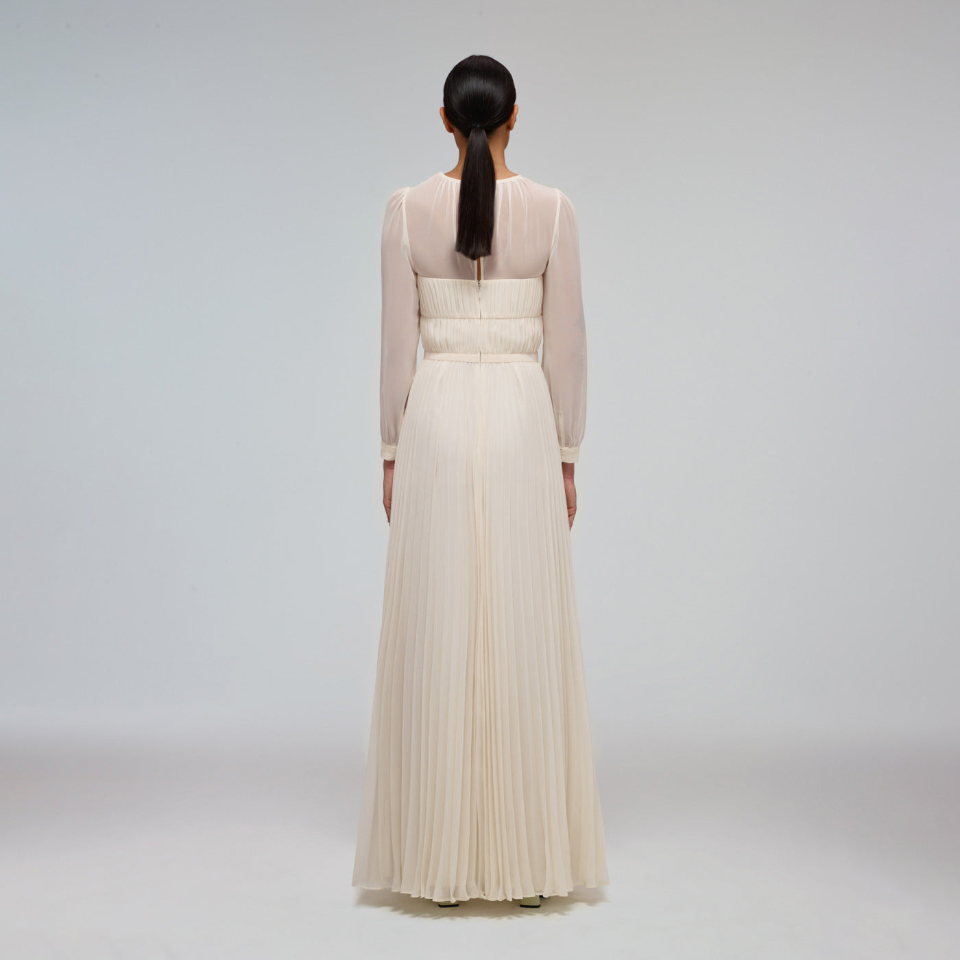 A woman wearing the Ivory Chiffon Pleated Maxi Dress