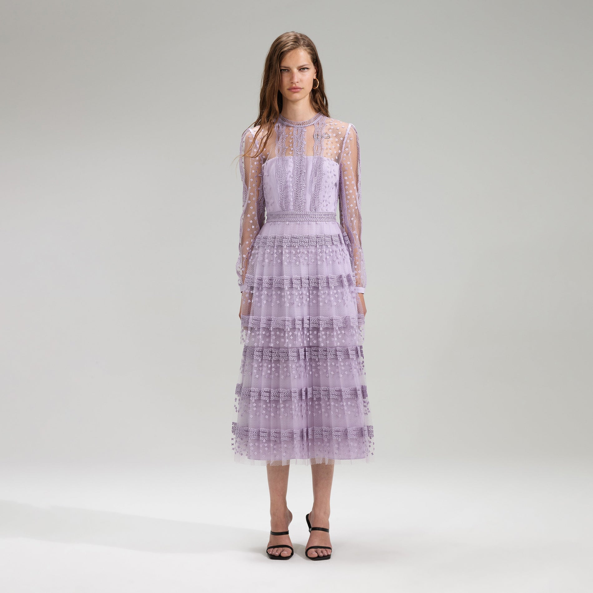 A woman wearing the Lilac Tiered Lace Midi Dress