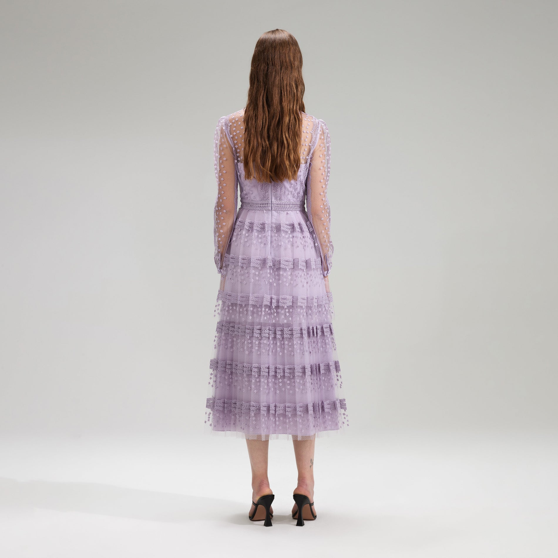 A woman wearing the Lilac Tiered Lace Midi Dress