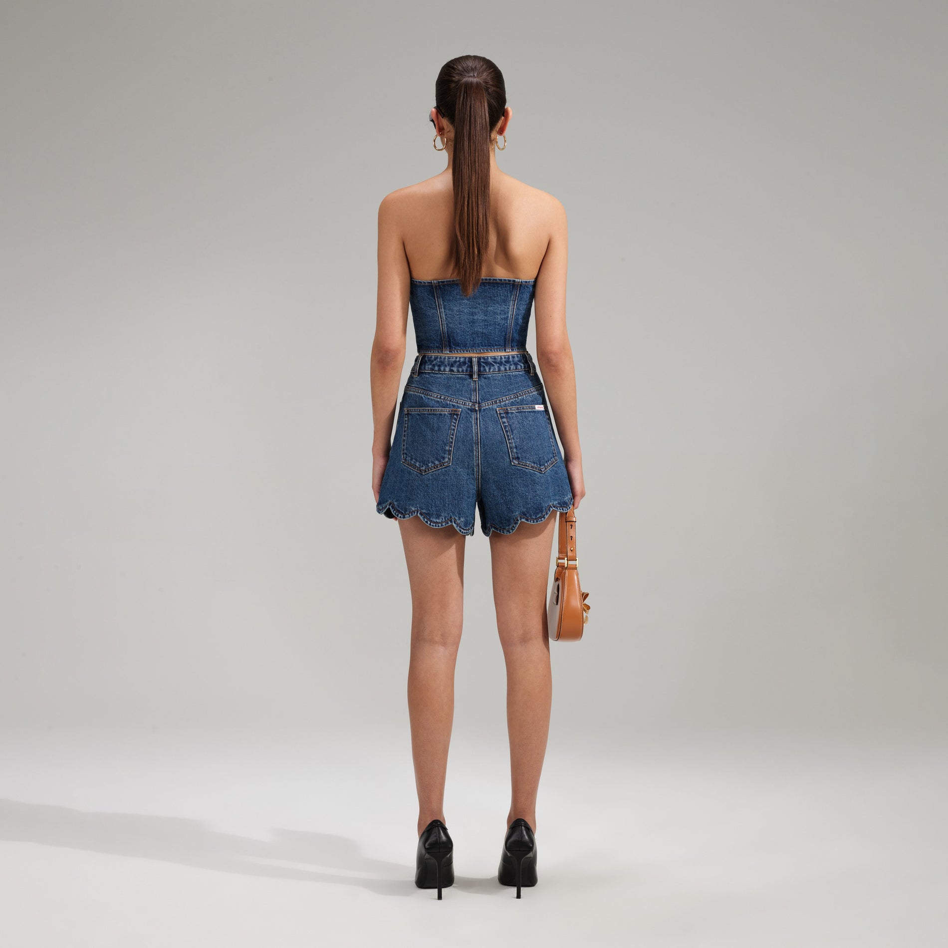A woman wearing the Bandeau Denim Crop Top With Scalloped Edge