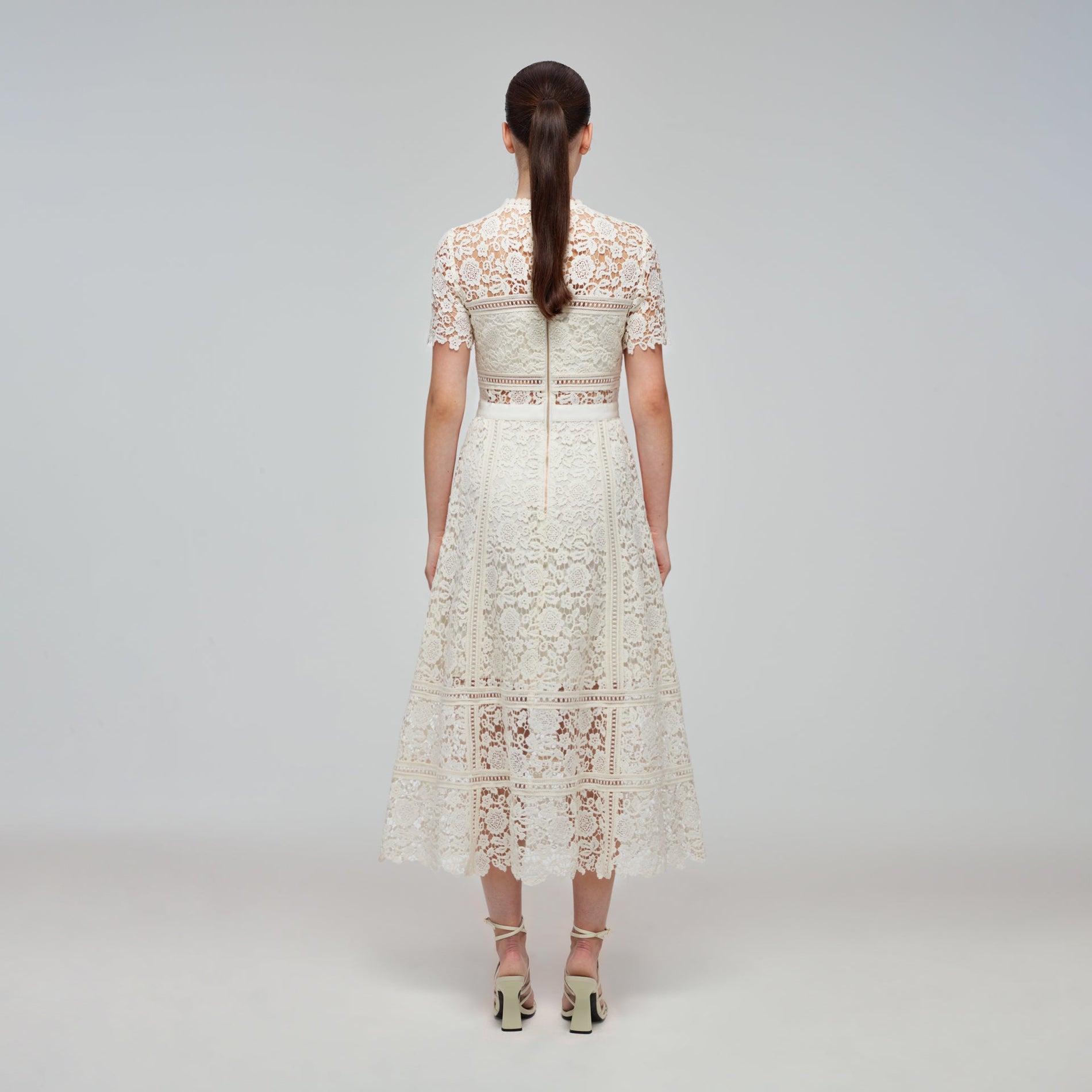 A woman wearing the Ivory Floral Guipure Midi Dress