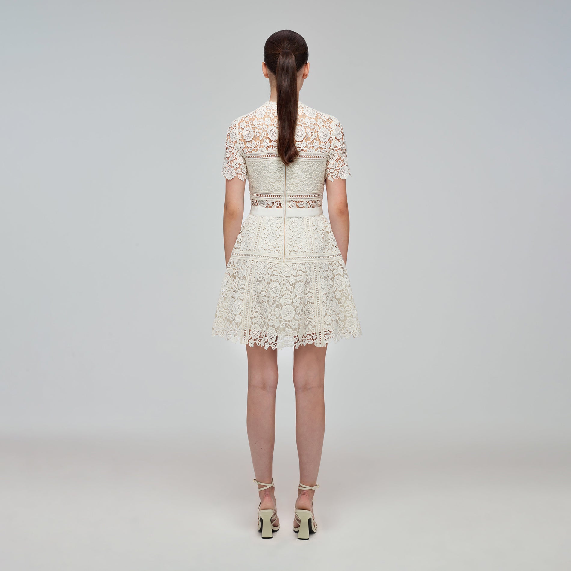 A woman wearing the Ivory Floral Guipure Mini Dress