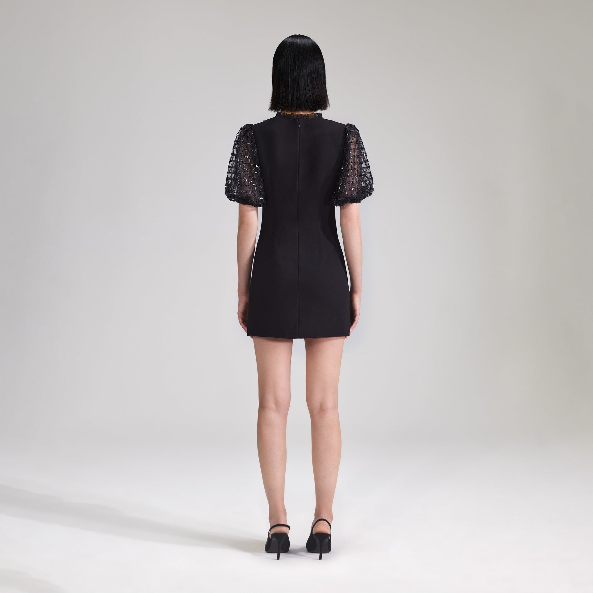 A woman wearing the Black Crepe Puff Sleeve Mini Dress
